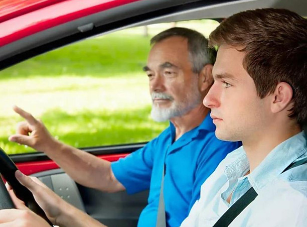 Instructor enseñando a conducir a un joven
